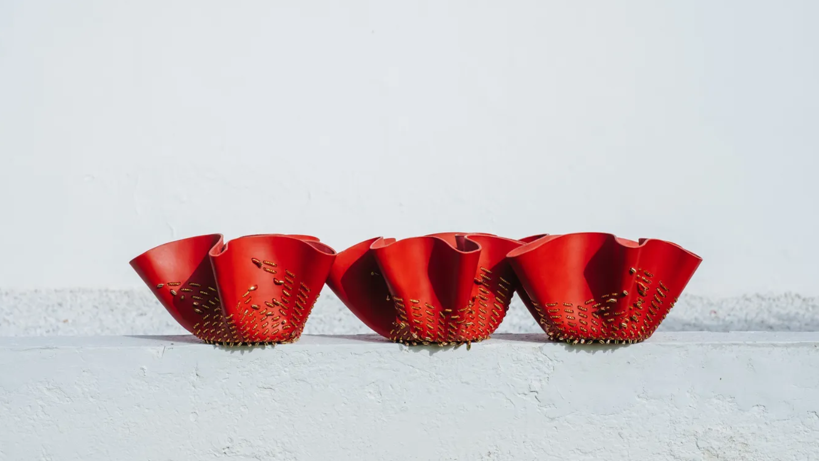 Fotografía de tres de los fruteros diseñados por Estudio Savage para Ciartier, con formas onduladas y color rojo intenso