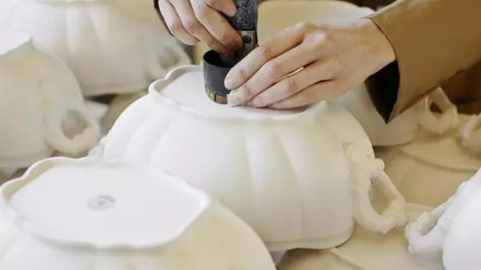 Fotografía de las manos de una artesana trabajando en piezas de cerámica blanca